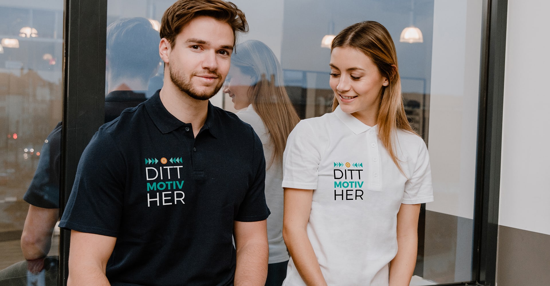 Ungt par sitter foran et vindu med personaliserte poloskjorter