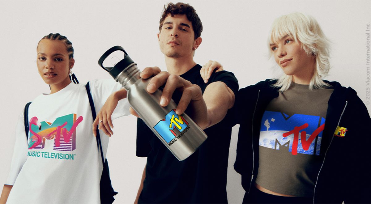 Two young women and a young man in a print T-shirt holding a silver-colored drinks bottle up to the camera. 