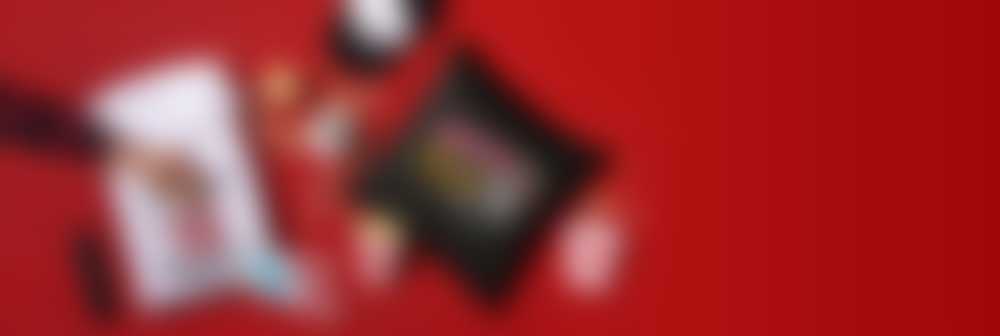 Hand mit Popcorn sowie Tasse, Hoodie, Cap und Kissen mit Aufdrucken für Filmfans vor rotem Hintergrund
