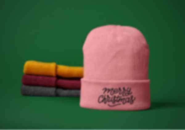 Embroidered Merry Christmas lettering on a pink cap against a green background