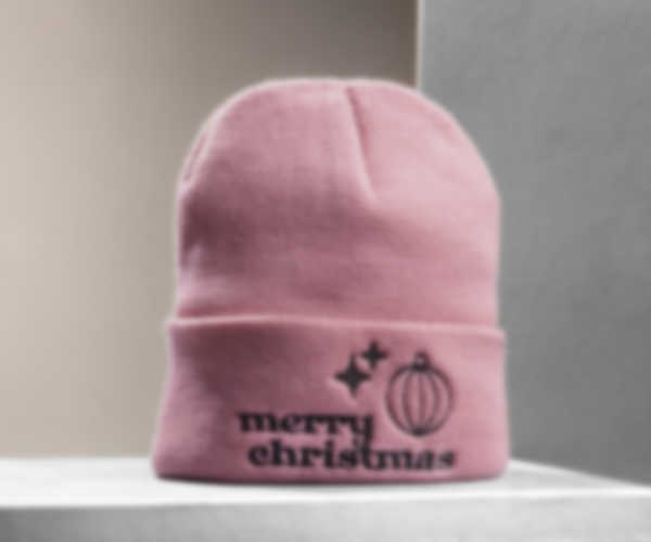 Gestickter Merry-Christmas-Schriftzug und weihnachtliche Motive auf pastellrosafarbener Mütze
