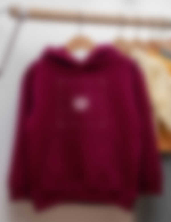 A maroon red children's hoodie with a customisation option in the centre