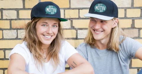 Et par sitter foran en vegg med egendesignede luer