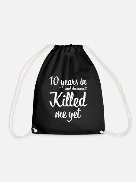 10 years in and she has not killed me yet gift - Drawstring Bag - black