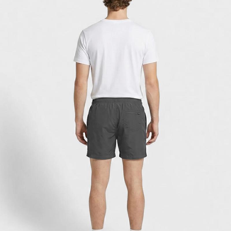 kleiner, blauer Hund pullert an eine Wand Badeshorts