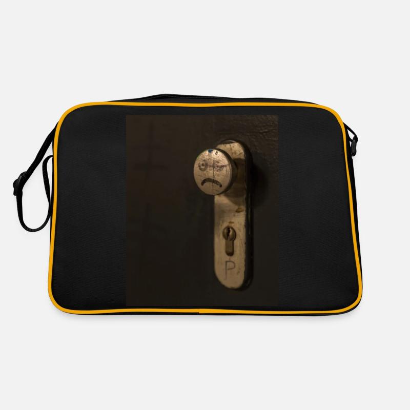 A doorknob with a bad tempered face painted on it - Retro Bag - black/gold